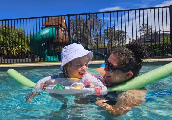 Woman and a girl happily playing in a pool