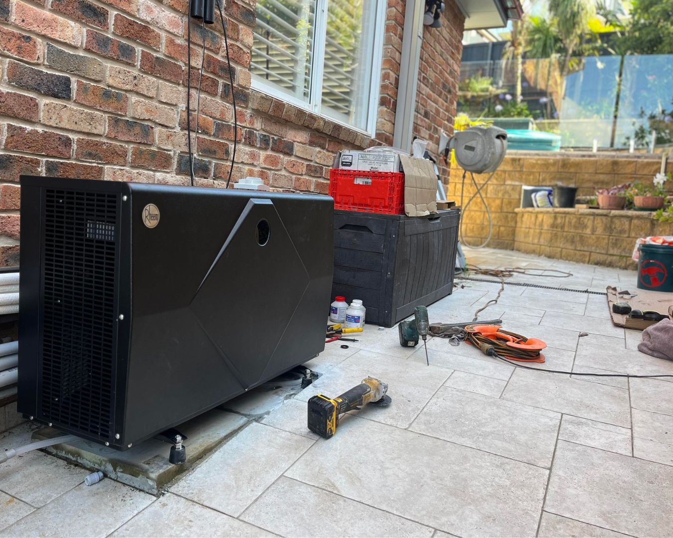 A pool heat pump being repaired with tools beside it