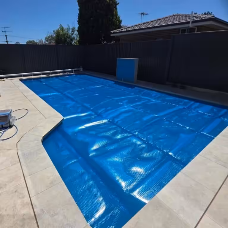 Backyard swimming pool with blue solar cover