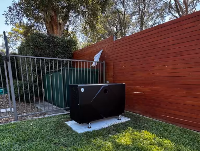 Rheem pool heat pump unit positioned in a corner near a pool